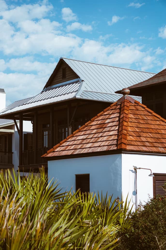 Florida coastal-style home with a cedar shake roof in the foreground and a standing-seam metal roof behind