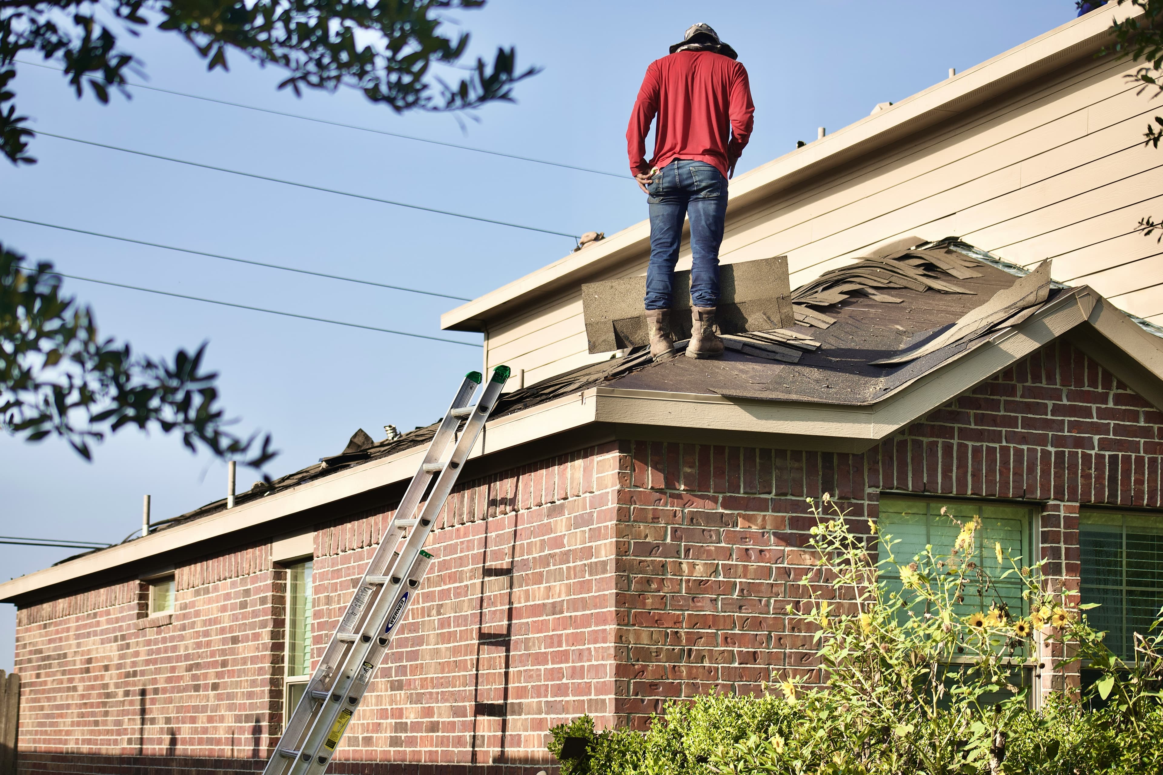 Roofer removing old shingles during a property reroofing project