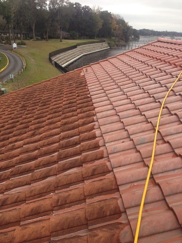 Aerial view of a tile roof showing a cleaned, restored section next to weathered, algae-stained tile