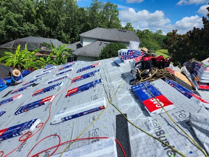 Roofing crew installing GAF synthetic underlayment during a new roof installation
