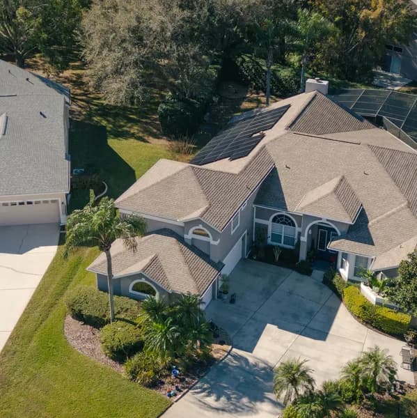 Aerial view of a completed roof replacement with solar panels on a Northeast Florida home